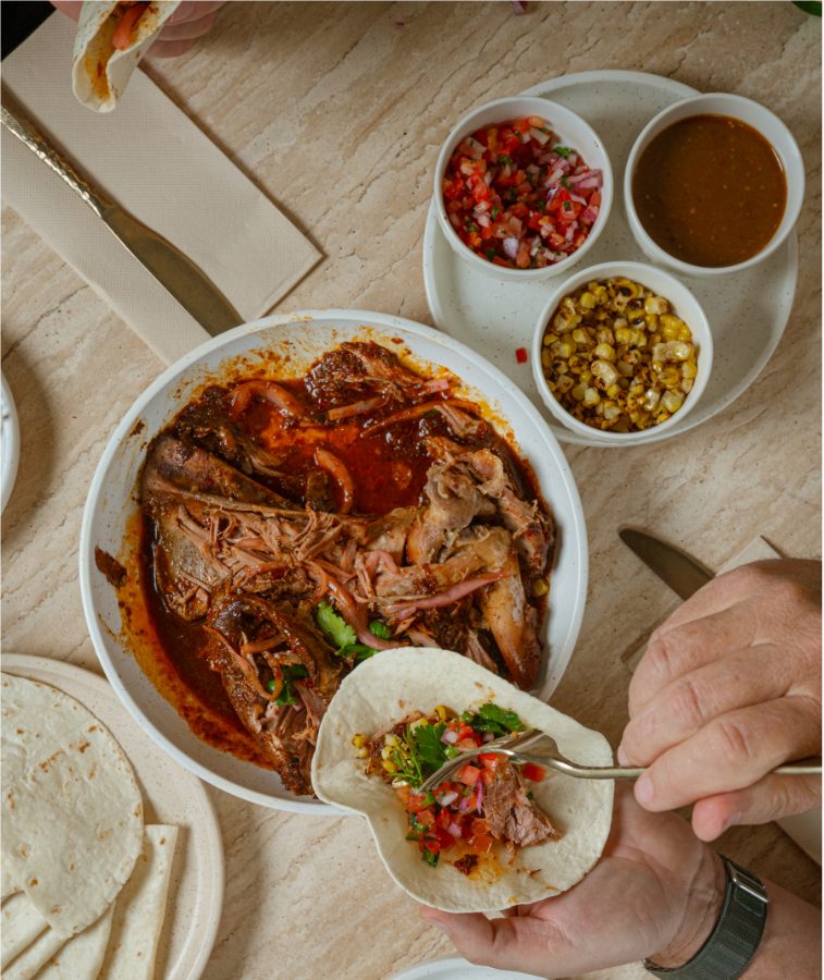 Slow-cooked beef in red sauce with a side of corn at Angelica Norwest