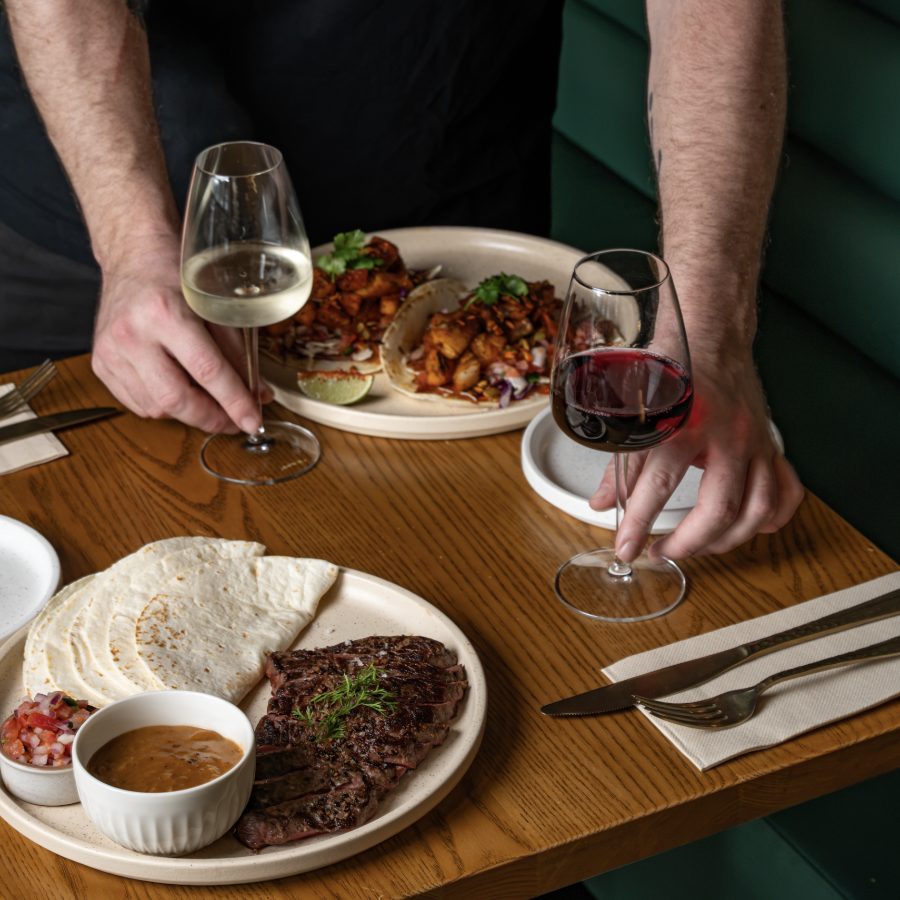 Two people dining with red wine at a timber table at Angelica Norwest