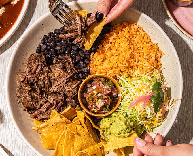 Bowl of slow-cooked beef with rice, salsa and shredded lettuce