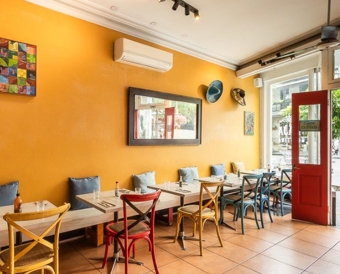 Yellow dining room with a red door and framed pictures at Baja Cantina Glebe