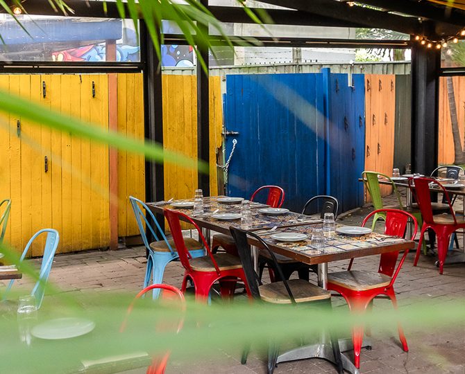 Outdoor courtyard tables against yellow and blue doors at Baja Cantina Glebe